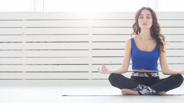 Sporty Young Woman Practicing Yoga, Sitting in Half Lotus Exercise, Siddhasana Pose, Indoor, Home