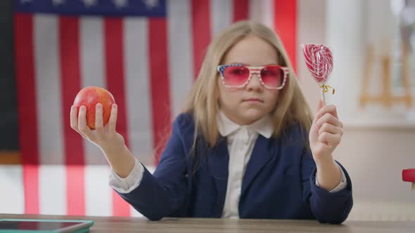 Healthful Apple and Unhealthy Sweet Lollipop in Hands of Blurred Teenage Schoolgirl Choosing Snack