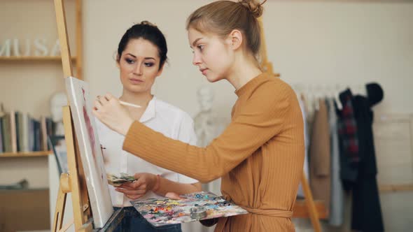 Charming Art Student Girl Is Painting in Studio Under Guidance of Experienced Female Teacher. Master