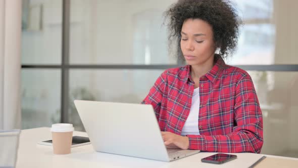 African Woman Thinking While Working on Laptop