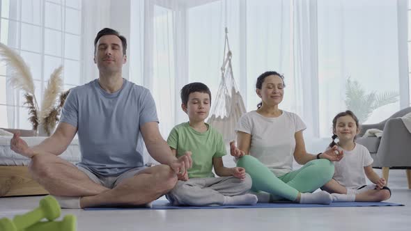 Attractive Family with Children Doing Yoga Indoors