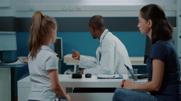 African American Medic Giving Bottle of Pills to Mother with Girl