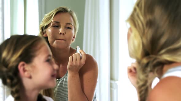 Mother and daughter applying lipstick in bedroom 4k