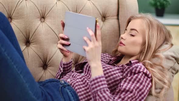Relaxed Woman Lying on Couch Using Tablet Pc Enjoying Weekend