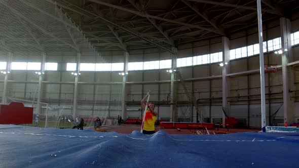 Pole Vaulting - Sportsman in Yellow t Shirt Is Running and Jumping Over the Bar