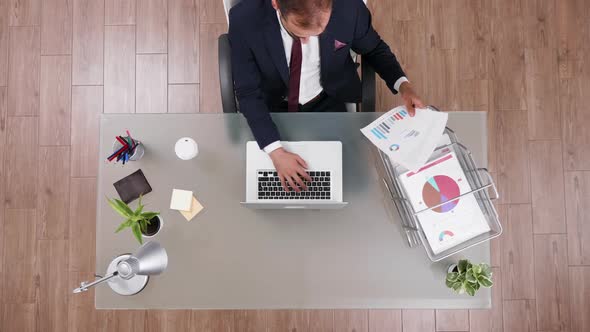 Top View Businessman Typing and Reading Data From a Chart