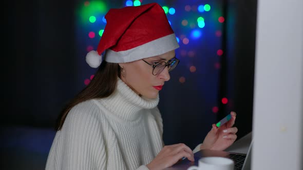 Woman Holding Credit Card and Using Laptop in Home at Night