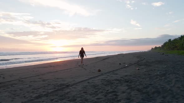 Young woman coming back from the warm south pacific ocean during sunset and walking towards the came