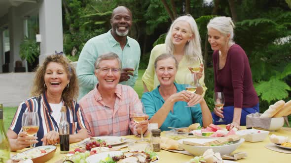 Animation of diverse happy senior female and male friends eating lunch in garden