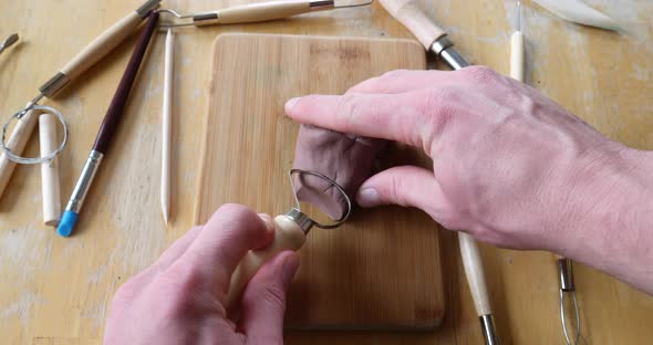 Close up on the hands of an artist or sculptor cutting and carving a strangely satisfying soft brown