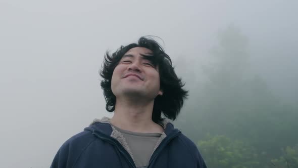 Male traveller flicks hair at the top of mountain with thick fog in the early morning.