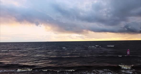 Windsurfer Rides the Waves During a Storm at the Setting Sun