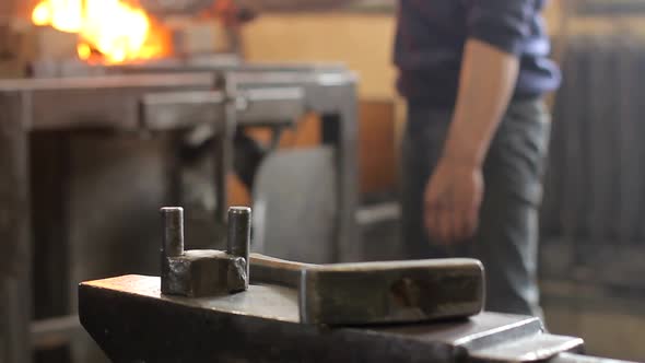 Heavy Industrial Forging Worker in Protective Gloves Takes the Hot Ingot with Industrial Sissors