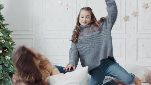 Smiling Ladies Starting Pillow Fight on Bed in Luxury Apartment.