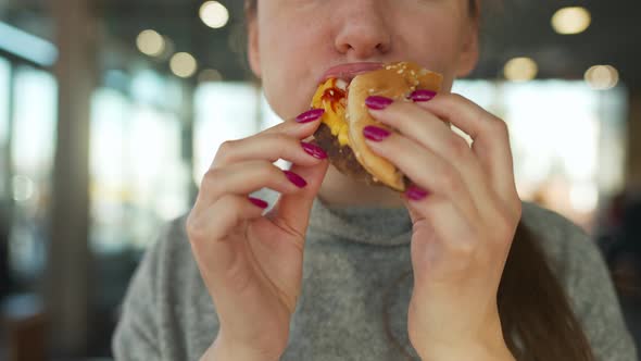 Woman Eating Hamburger and Fries in a Cafe Closeup