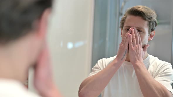 Rear View of Upset Young Man Looking Himself in Mirror 