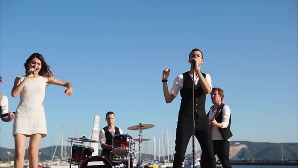 Modern Musicians Perform a Song Near the Sea at a Corporate Party in the Daytime