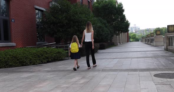 Happy Little Caucasian Blonde Girl Seven Years Old in Uniform with Yellow Backpack Going Back to