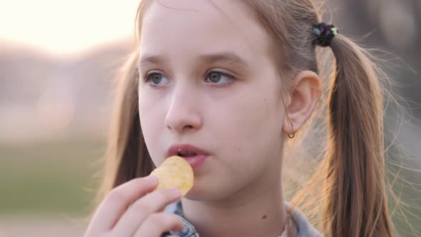 Young School Girl Eating Chips From Packet on Street