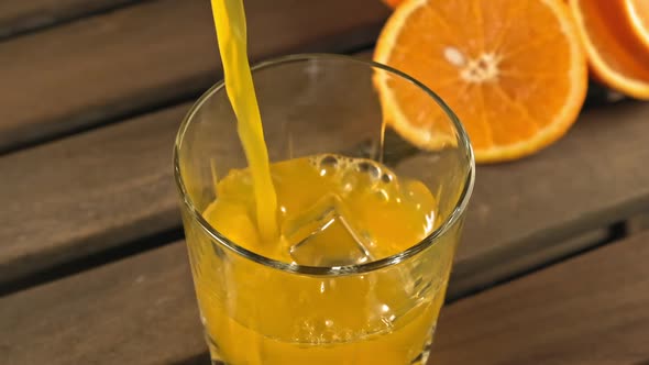 Orange Juice Being Poured in Glass with Ice Cubes. Organic Drink Concept