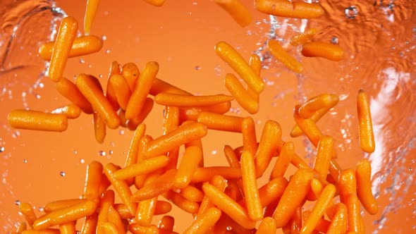 Super Slow Motion Shot of Flying Fresh Baby Carrots and Water Side Splash at 1000 Fps