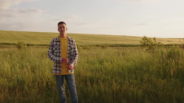 Happy Man Crosses His Hands on the Green Field