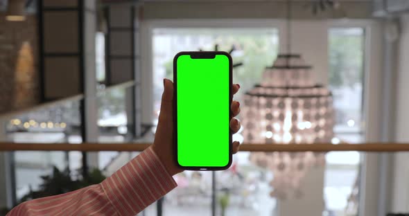 POV of Woman at Modern Room Sitting on a Chair Using Phone With Mock-up Green Screen.