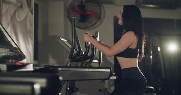 Athletic Girl Training Fast on Steppers in a Dark Gym with a Backlit