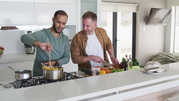 Multi ethnic gay male couple preparing food in kitchen