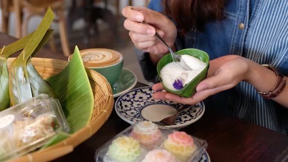 A woman eating Thai pudding with coconut milk topping in cafe