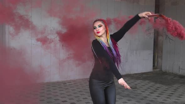 A Girl in a Simple Black Dress with Colored Braids and Rainbow Makeup Posing in Red Thick Smoke in a