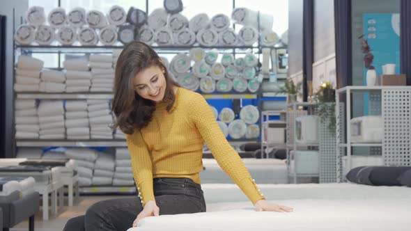 Beautiful Woman Smiling to the Camera Sitting on a New Bed at Furniture Store