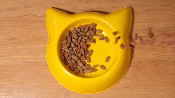 Pet Food Falls Down Into A Yellow Pet Bowl On A Floor