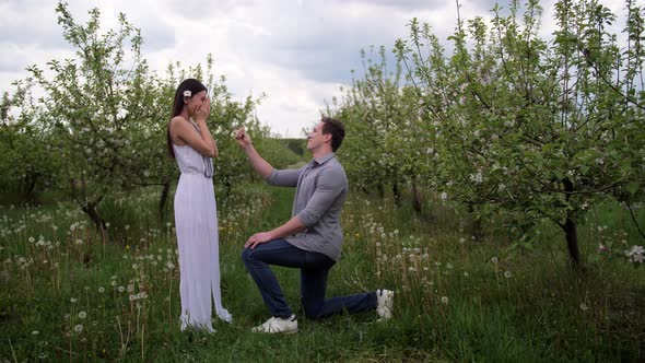 Man Making Marriage Proposal To Woman in Orchard