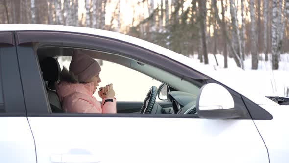 Woman Blowing on Her Hands Inside Car in Winter