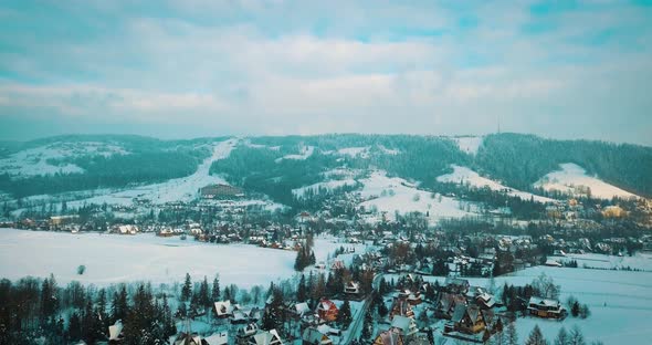Cinematic view of the mountains and a small town in the snow in winter
