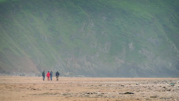 People Walking On Beach Near Cliffs