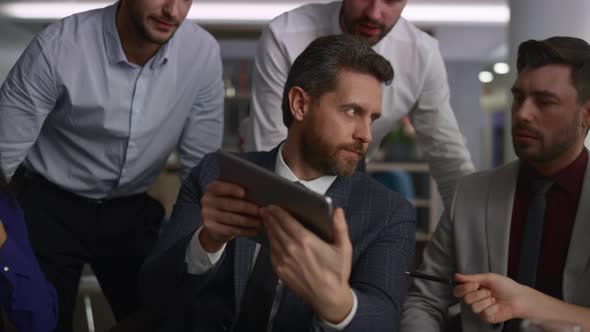 Multiracial Coworkers Group Researching Corporate Data Using Tablet in Office