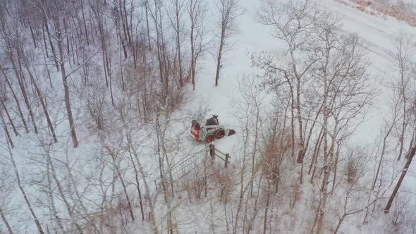 Clearing snow on a rural property with a wheeled bobcat