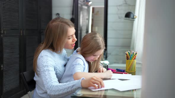 Caring Young Mother Helping Little Daughter Drawing Picture Using Colorful Pencil Medium Shot