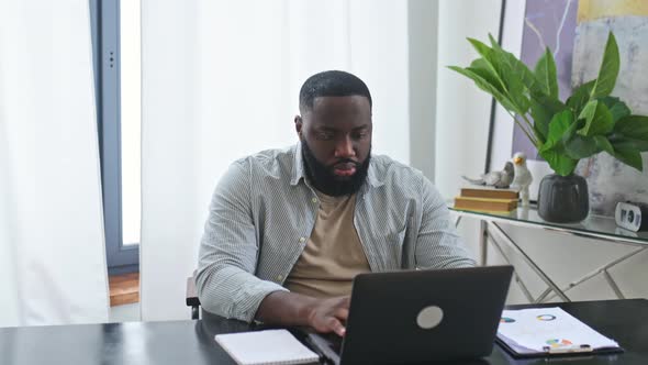 Amazed Happy Emotional African American Stylish Man Trader Student Freelancer Sitting at Table with