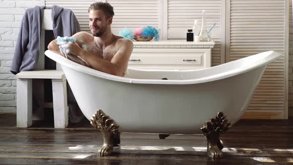 Happy Young Man Washing in Bathrobe in Bathroom. Hygiene and Spa. Care of Skin, Morning. Naked Guy