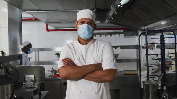 Portrait of mixed race male chef wearing face mask with arms crossed