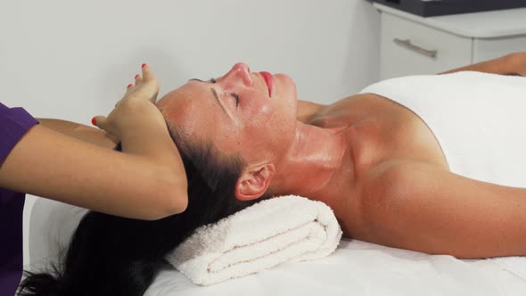 Happy Mature Woman Receiving Head and Neck Massage