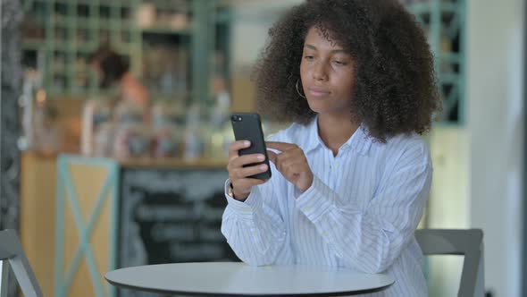 Serious African Woman Using Smartphone in Cafe 