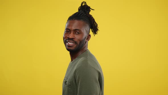 Side View of Handsome African American Man Turning to Camera and Smiling Posing at Yellow Background