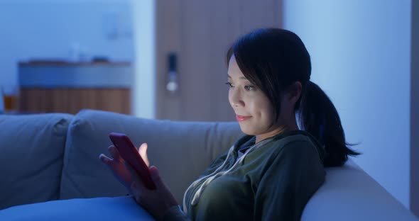 Woman use smart phone online and sit on sofa couch at home