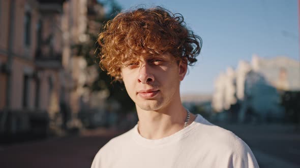 Young Curlyhaired Man Looks Straight with Smile Closeup