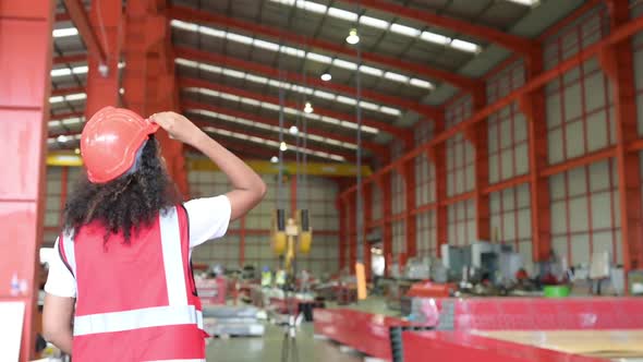 Young woman engineers testing and checking the operation of crane in the factory.