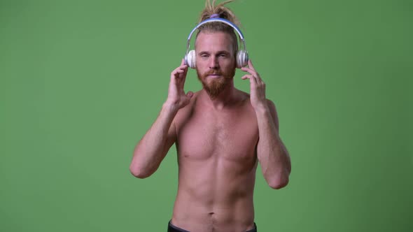 Handsome Muscular Bearded Man with Dreadlocks Listening To Music Shirtless